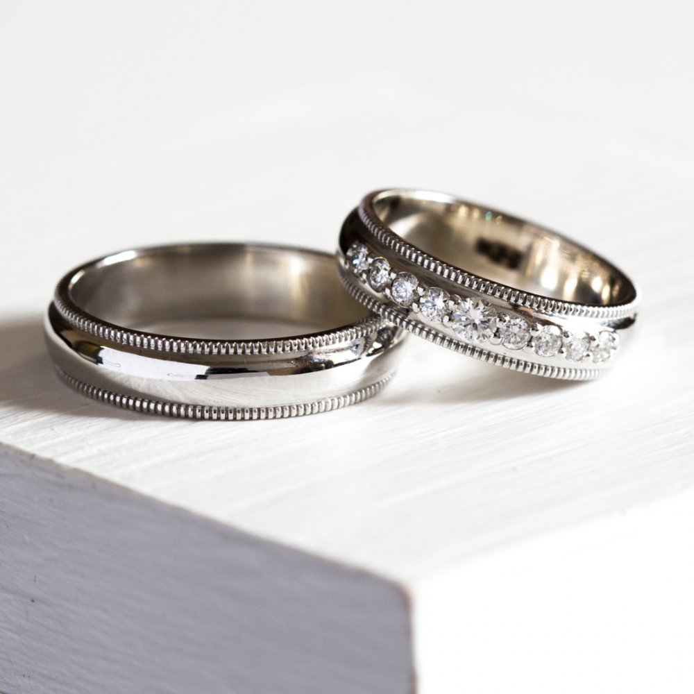 Обручальные кольца в классическом стиле, выполнены из белого золота, женское кольцо украшено девятью бриллиантами. 