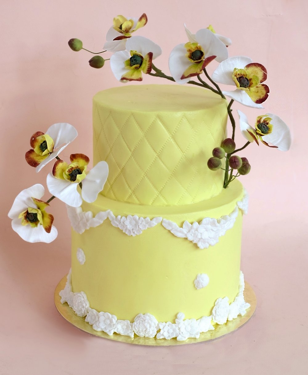 Торт лимонного цвета в классическом стиле с белой лепниной, стеганным верхним ярусом и белыми сахарными орхидеями