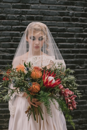 Роковая невеста с раскидистым свадебным букетом с протеей и орхидеями