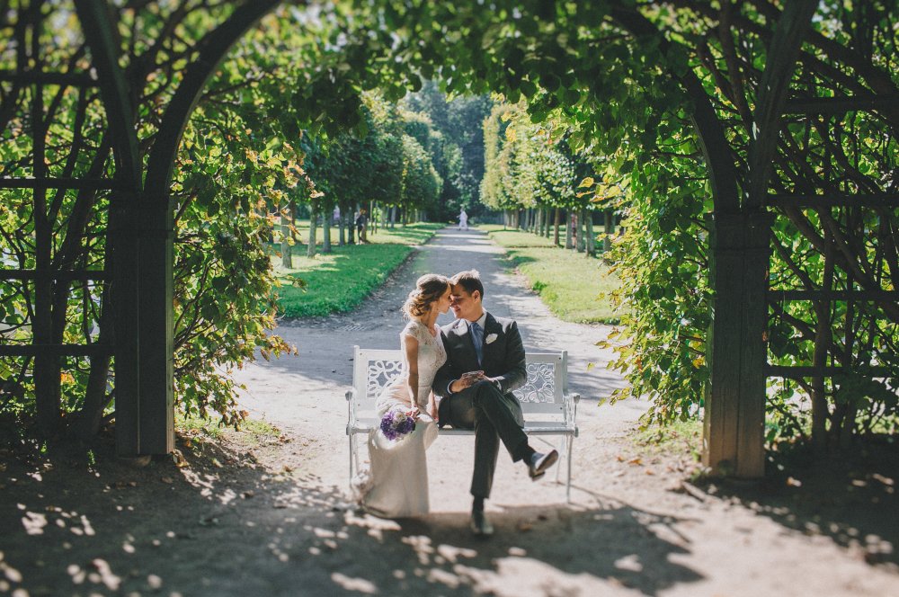 Жених и невеста на скамье в городском парке