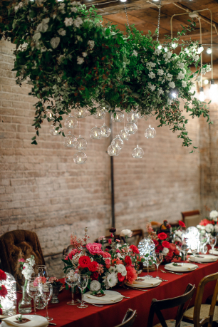 Подвесная люстра из зелени и оформление общего стола на камерной свадьбе в красивом лофте