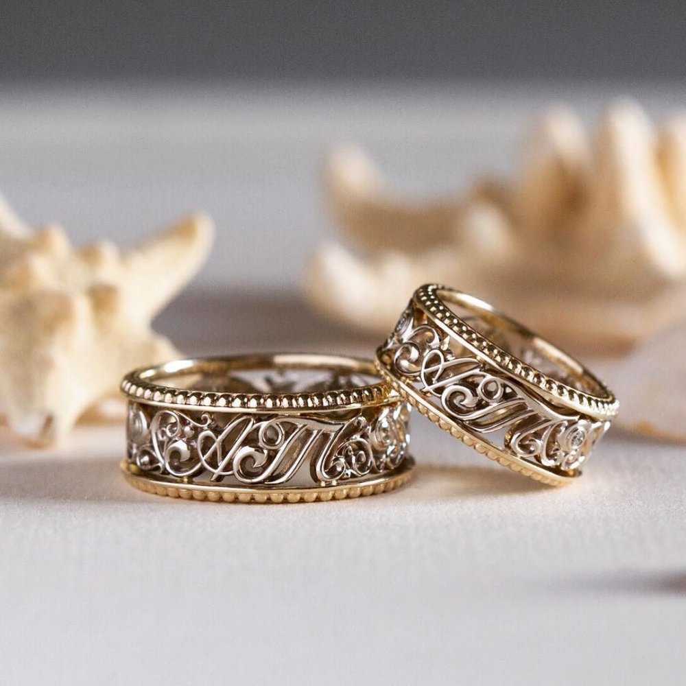 Обручальные кольца с инициалами, выполнены из жёлтого и белого золота 585 пробы. Женское кольцо украшают шесть бриллиантов по 1,5 мм каждый.