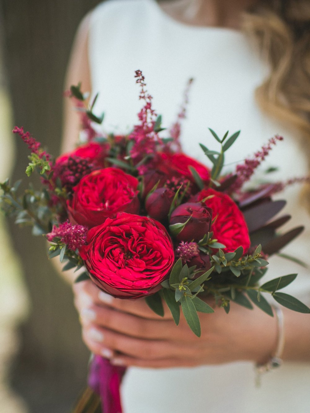 Яркий и грациозный букет невесты из бордовых пионовидных роз "Piano", скиммии, астильбы и эвкалипта. Декорирован атласной лентой и кружевом. 