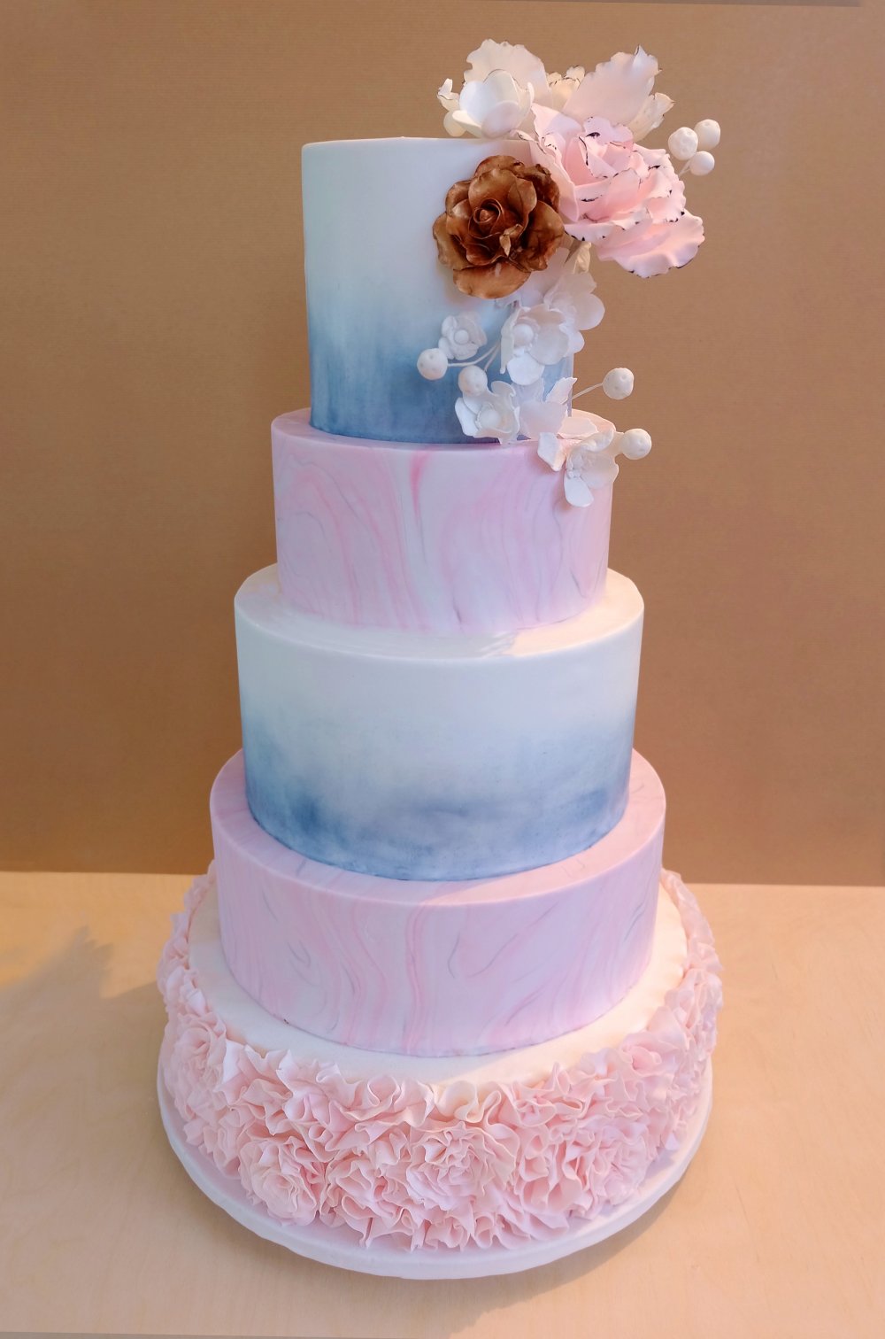 Большой свадебный торт с мраморными розовыми ярусами и белыми ярусами с голубой акварелью. Композиция из сахарных цветов и нижний ярус в тонких сахарных рюшах