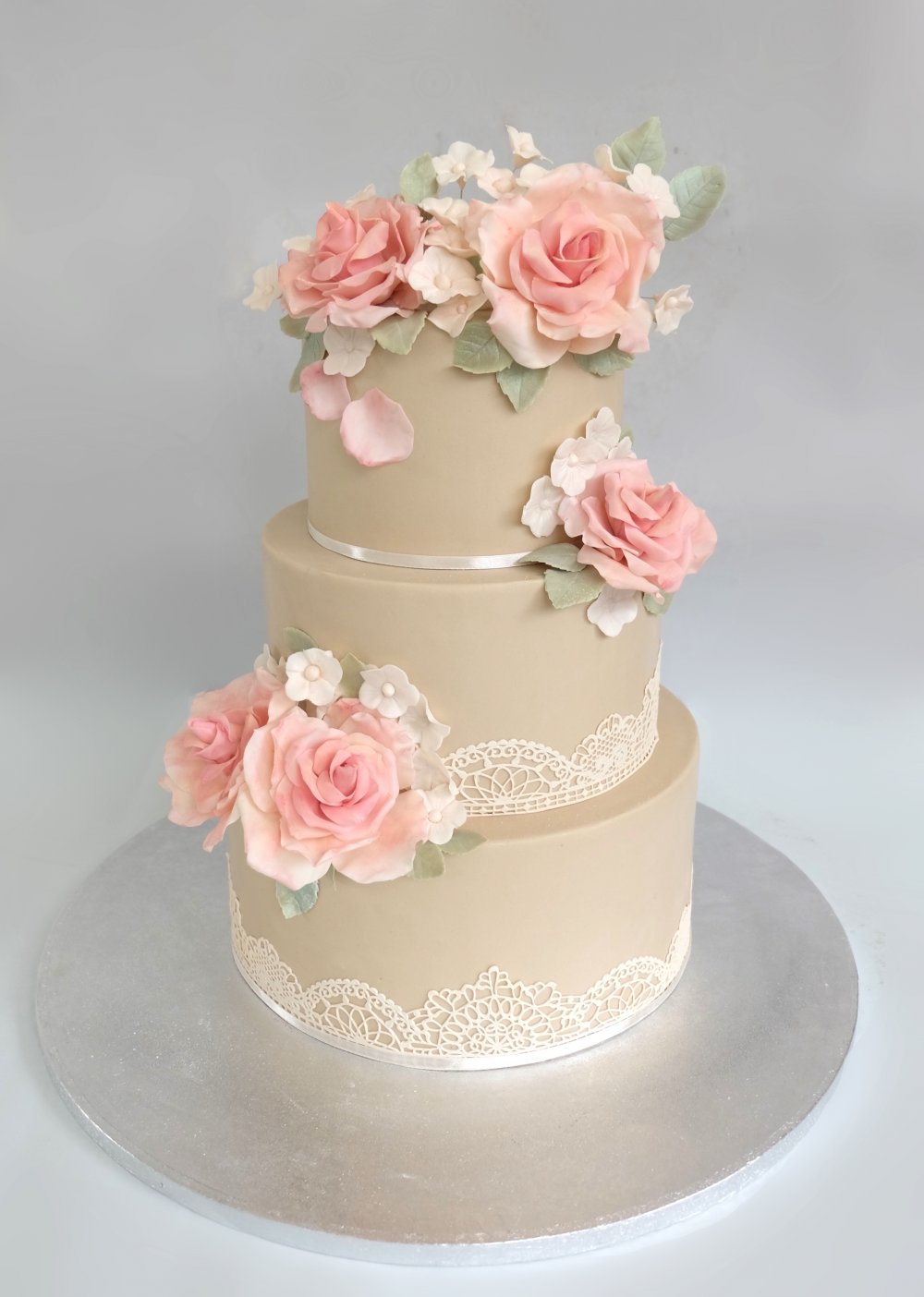 Нежный торт в приглушенной гамме с сахарными цветами, обтяжкой сложного бежевого цвета и сатиновыми лентами.